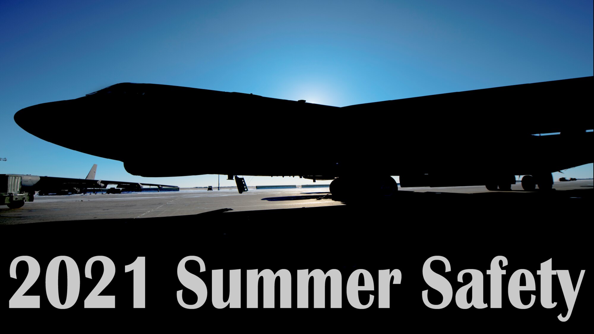 Sun rising behind B52 Stratofortress silhouette. Text 2021 Summer Safety