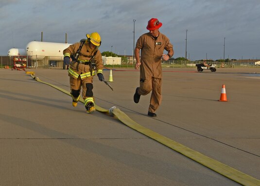 A fire protection student assigned to the 312th Training Squadron checks the tightness of hose connectors during a training exercise on Goodfellow Air Force Base, Texas, June 11, 2021. The student’s instructor ran next to him to evaluate the student’s understanding of the course objectives. (U.S. Air Force photo by Senior Airman Abbey Rieves)