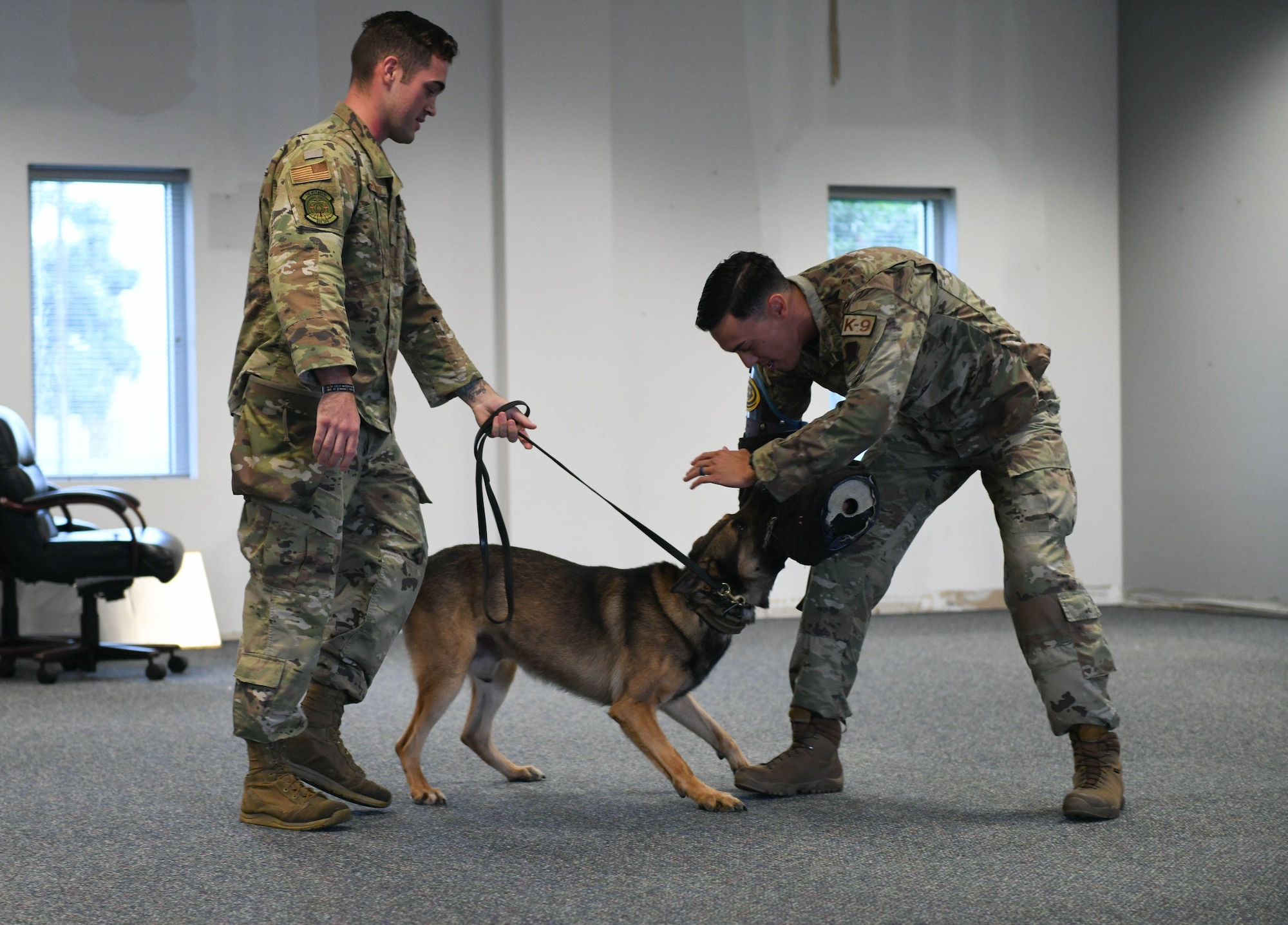 U.S. Air Force Senior Airman Spencer Harwood (left) and Staff Sgt. Matthew Baxter (right), 325th Security Forces Squadron military working dog handlers, conduct a MWD demonstration for Junior Leadership Bay members at Tyndall Air Force Base, Florida, June 22, 2021. JLB toured Tyndall to get a better understanding of the role Tyndall plays in the local community and learn more about Air Force opportunities after high school. (U.S. Air Force photo by Airman 1st Class Anabel Del Valle)