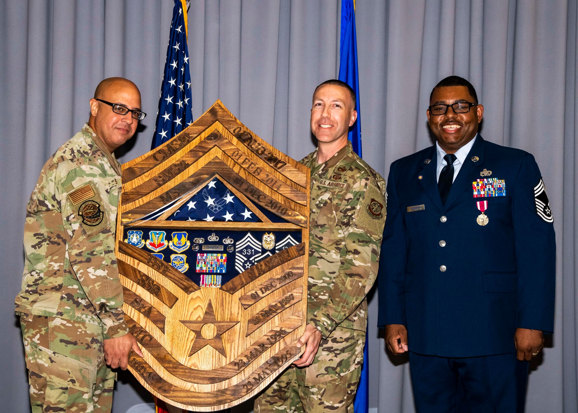 Senior Master Sgt. Michael Sierra, left, 436th Logistics Readiness Squadron materiel management flight chief, and Chief Master Sgt. Troy Dubois, middle, 436th LRS deployment and distribution flight chief, present a shadow box to Chief Master Sgt. Gary Thompson, right, 436th Mission Support Group superintendent, during his retirement ceremony at Dover Air Force Base, Delaware, June 18, 2021. The ceremony paid special tribute to Thompson's distinguished career spanning 26 years. (U.S. Air Force photo by Airman 1st Class Stephani Barge)