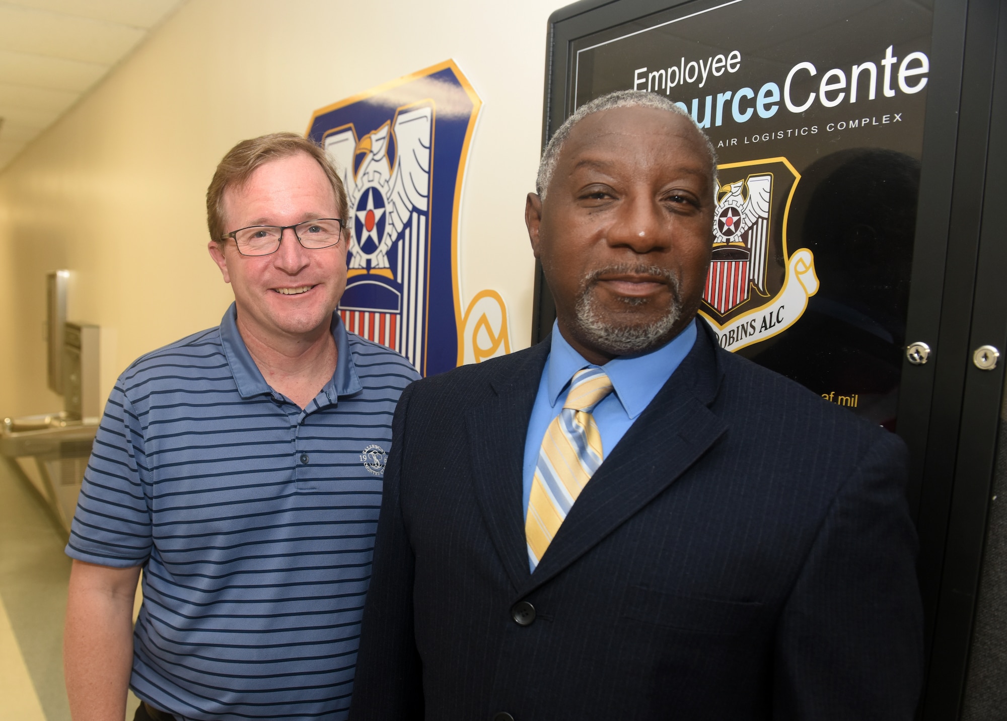 Photo shows two men standing in front of Employee Resource Center sign.