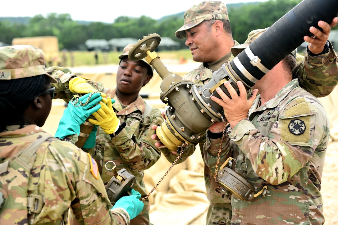 Soldiers wear gloves while packing up a fuel system.