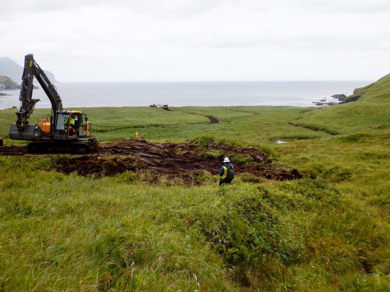 Crews work to recontour excavated areas to match the surrounding topography and replace the organic layer at the Cape Prominence Formerly Used Defense Site.