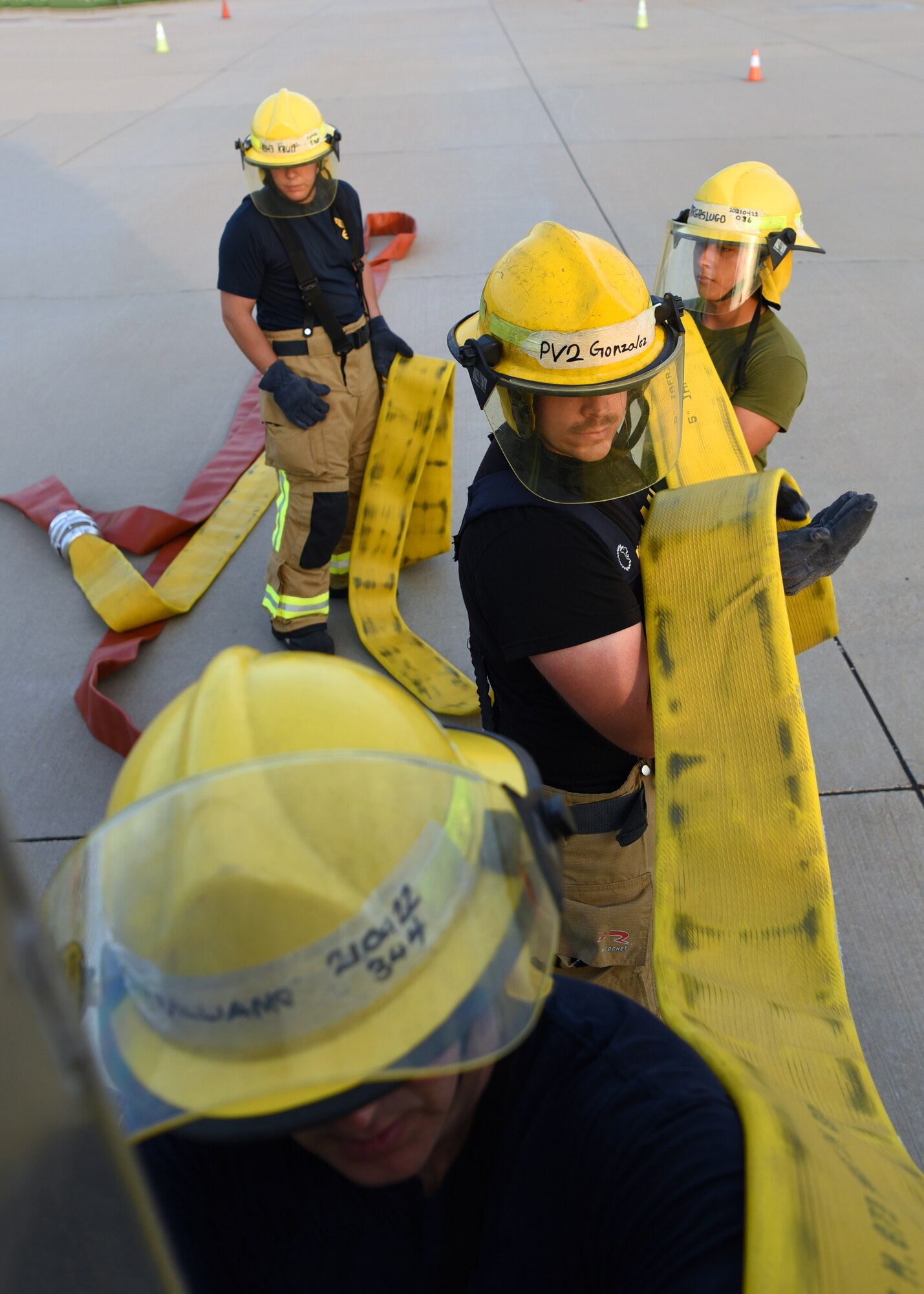 Joint service fire protection students from the 312th Training Squadron load a fire hose after a training on Goodfellow Air Force Base, Texas, June 11, 2021. The students fold the fire hose so it can be removed from the truck quickly during emergencies. (U.S. Air Force photo by Senior Airman Abbey Rieves)