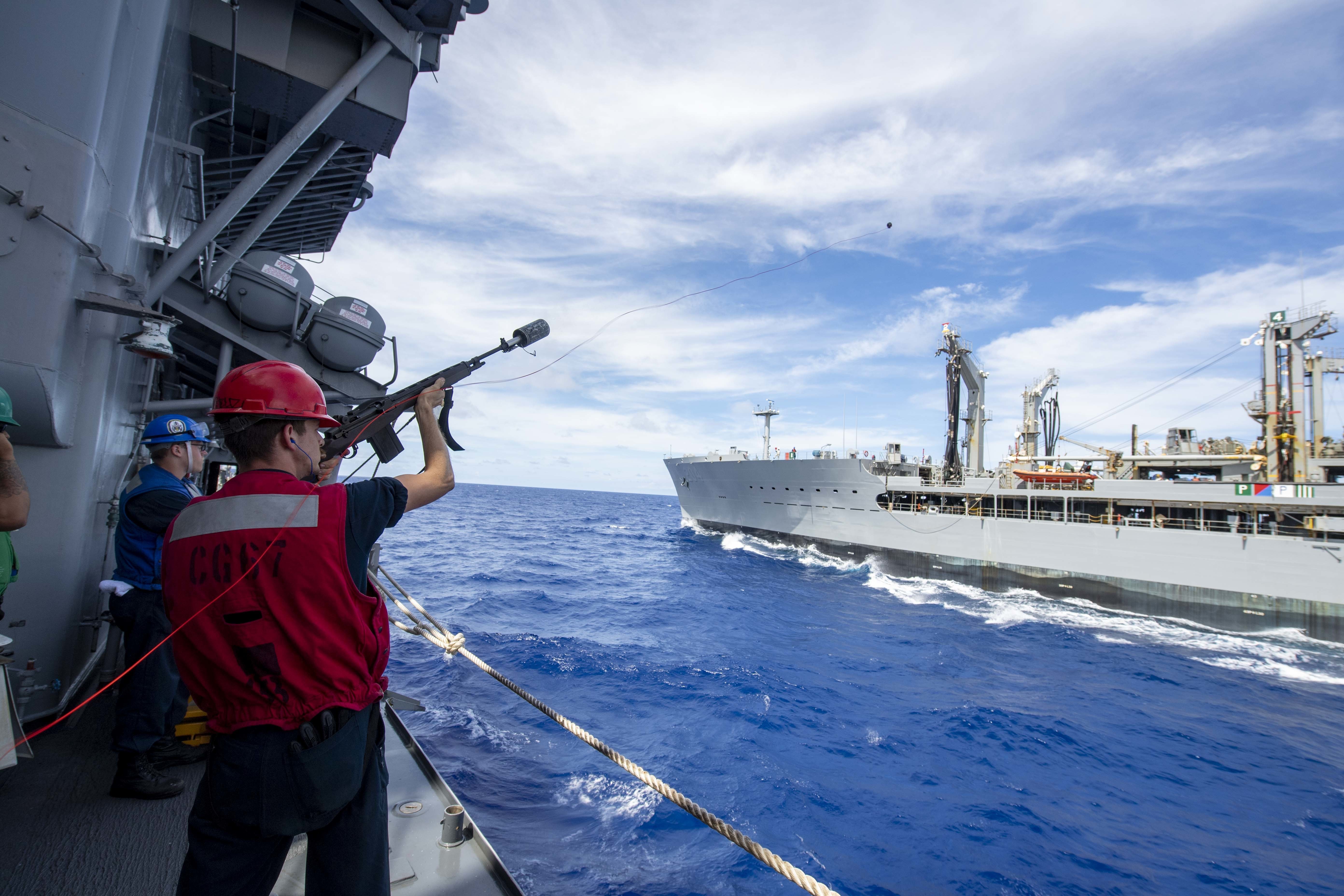 A Sailor fires a shot line to the Henry J. Kaiser-class replenishment oiler USNS Rappahannock (T-AO-204), from the Ticonderoga-class guided-missile cruiser USS Shiloh (CG 67).