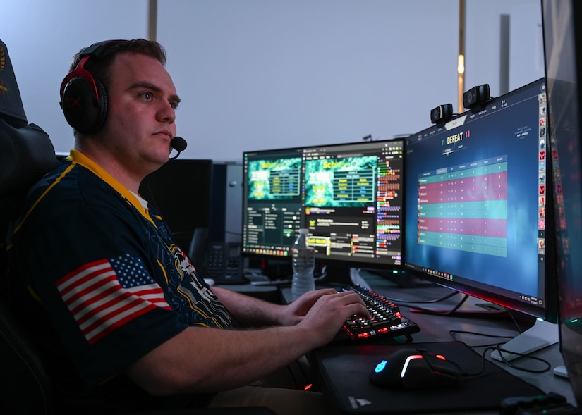A man in a headset plays a game on two monitors.