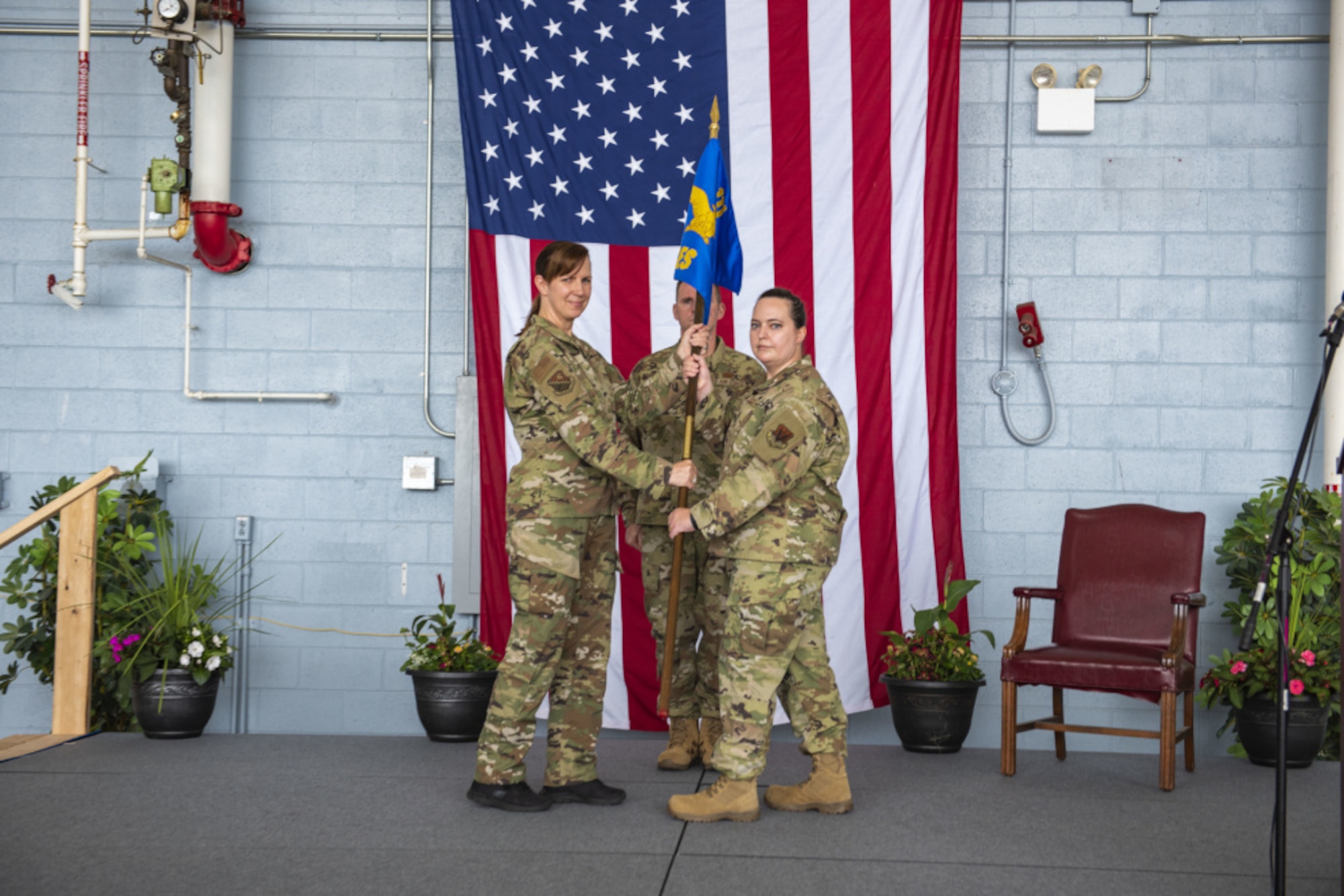A woman in a air force uniform passes a guidon to another woman in a air force uniform.
