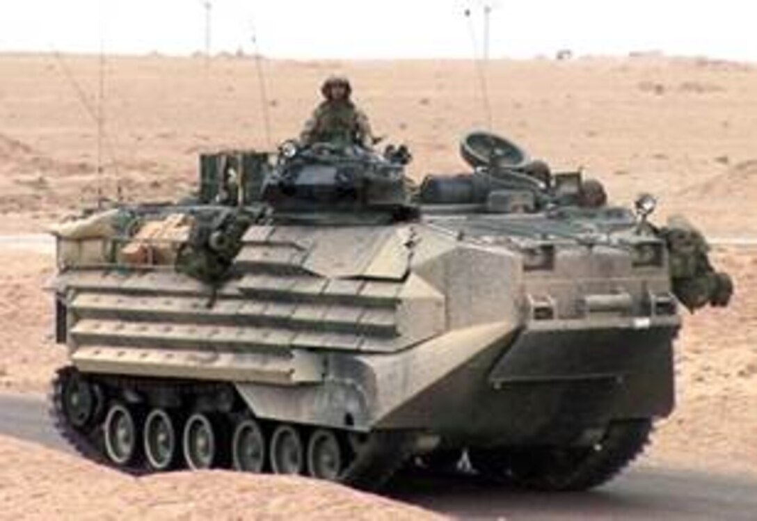 Light Armored Vehicle rolling down a paved road with a service member sitting on top.