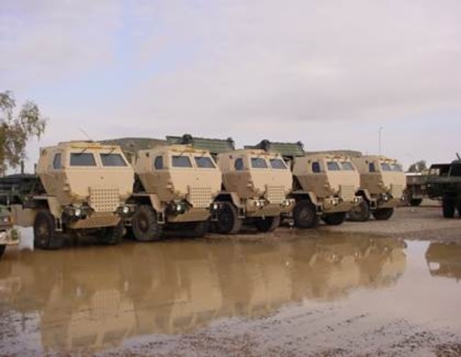 Five FMTV vehicles parked in a line.