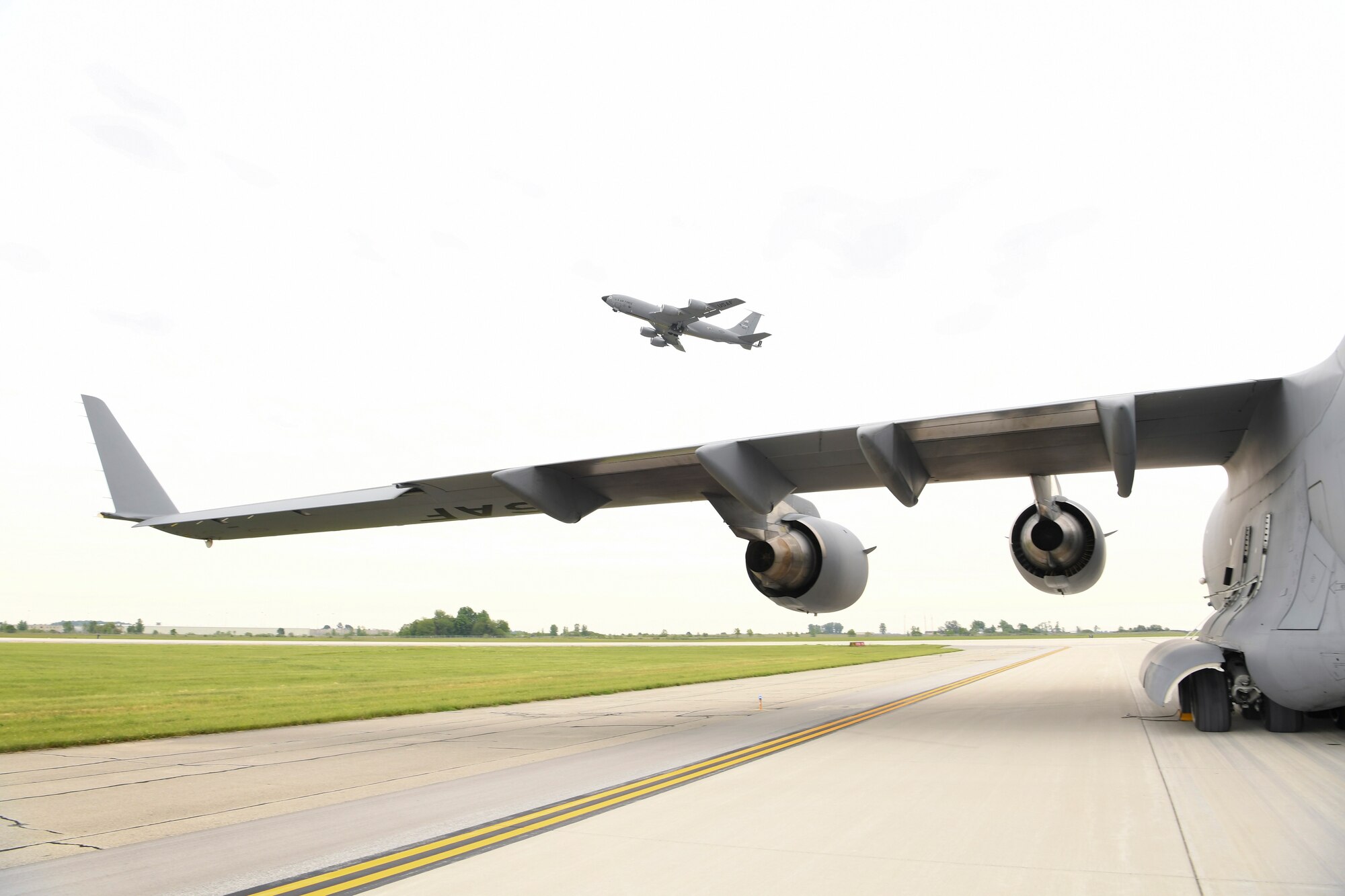 A Grissom KC-135R Stratotanker takes flight as a C-17 Globemaster II from the 512th Airlift Wing at Dover Air Force Base, Del., sits on the taxiway June 1, 2021. Members of Det. 1, 622nd Contingency Equipment Group, Dobbins Air Reserve Base, Ga., palletized and prepared the cargo for shipment to Hawaii to support a joint service exercise called Pacific Warriorz 2021.  (U.S. Air Force photo/Staff Sgt. Chris Massey)