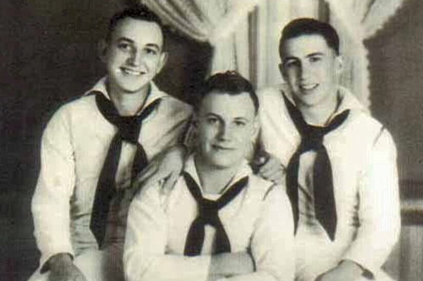 Three sailors smile at the camera.