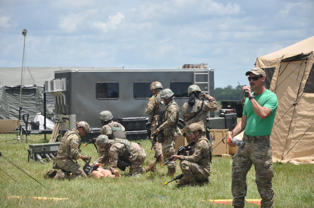 Photo shows Airmen working on a mannequin in a field.