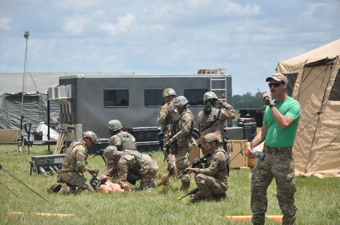 Photo shows Airmen working on a mannequin in a field.