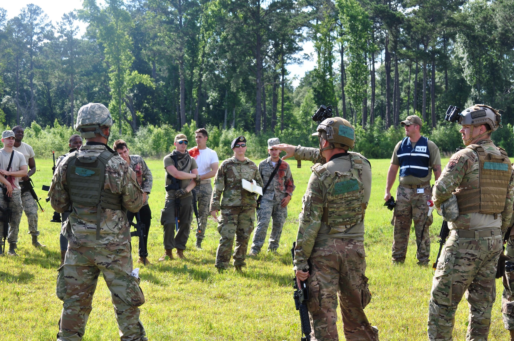 Photo shows group of Airman in battle gear standing in field.