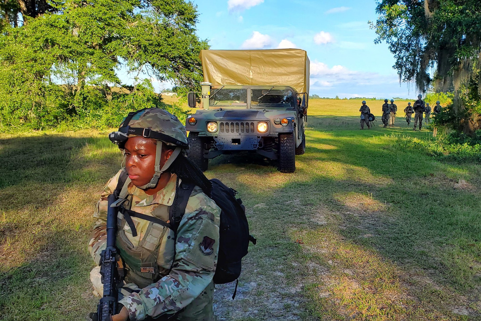 Photo shows Airman walking across field in front of a cargo truck.