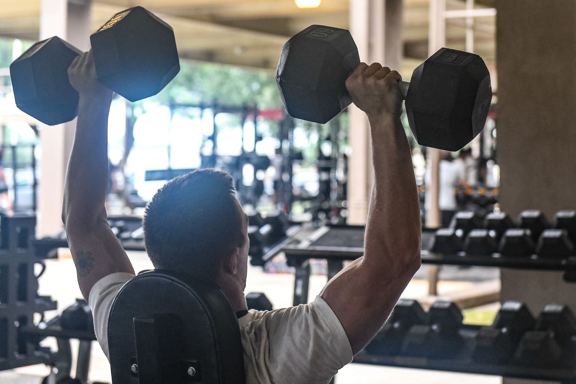 Training student lifting dumbbells over his head.