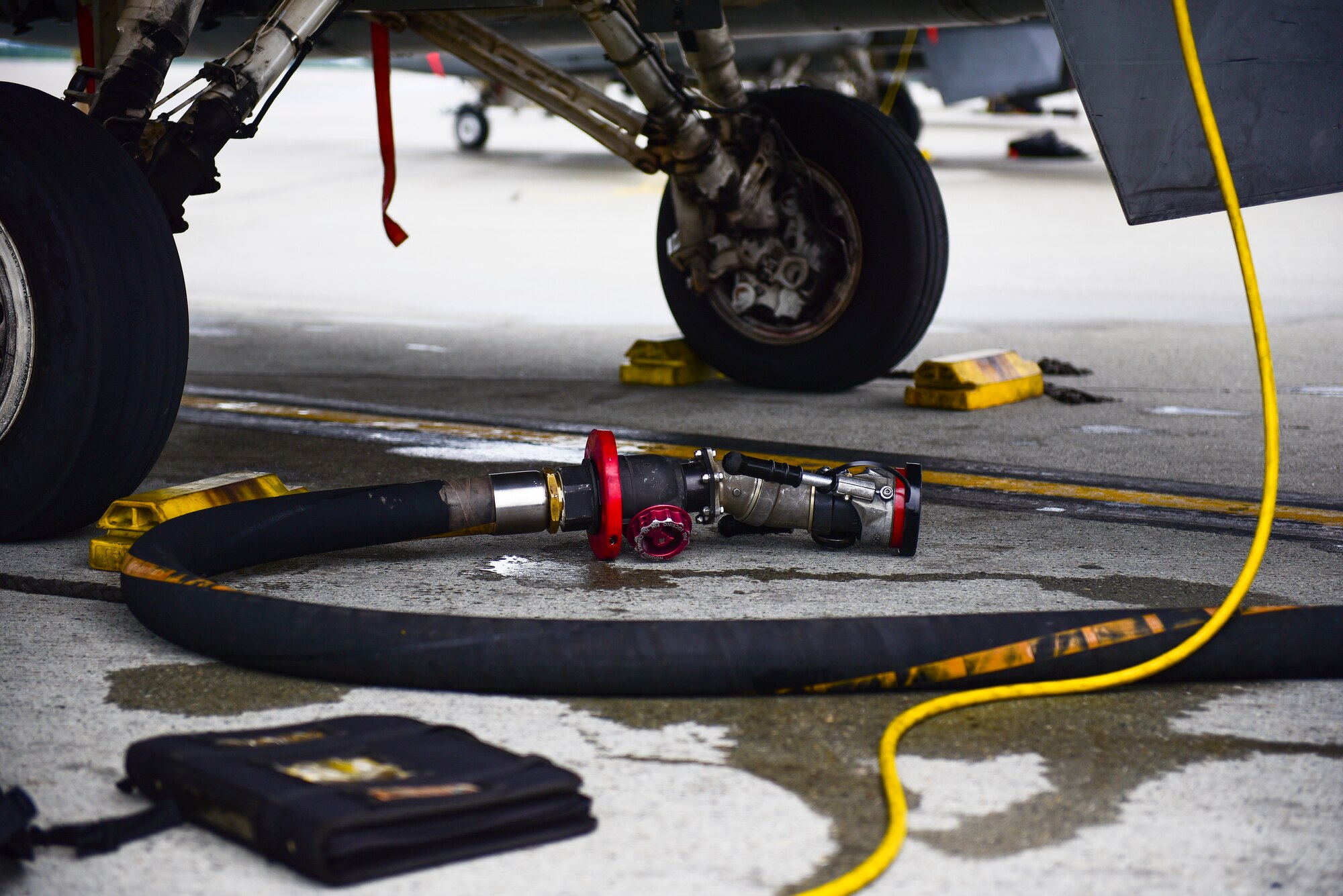 A fuel hose lays on the ground underneath an F-16 Fighting Falcon assigned to Kunsan Air Base, Republic of Korea, at Eielson Air Force Base, Alaska, June 18, 2021. Laboratory petroleum, oil and lubricants Airmen ensure the fuels distributed to aircraft are safe and within guidelines to ensure the F-16’s mission success. (U.S. Air Force photo by Senior Airman Suzie Plotnikov)