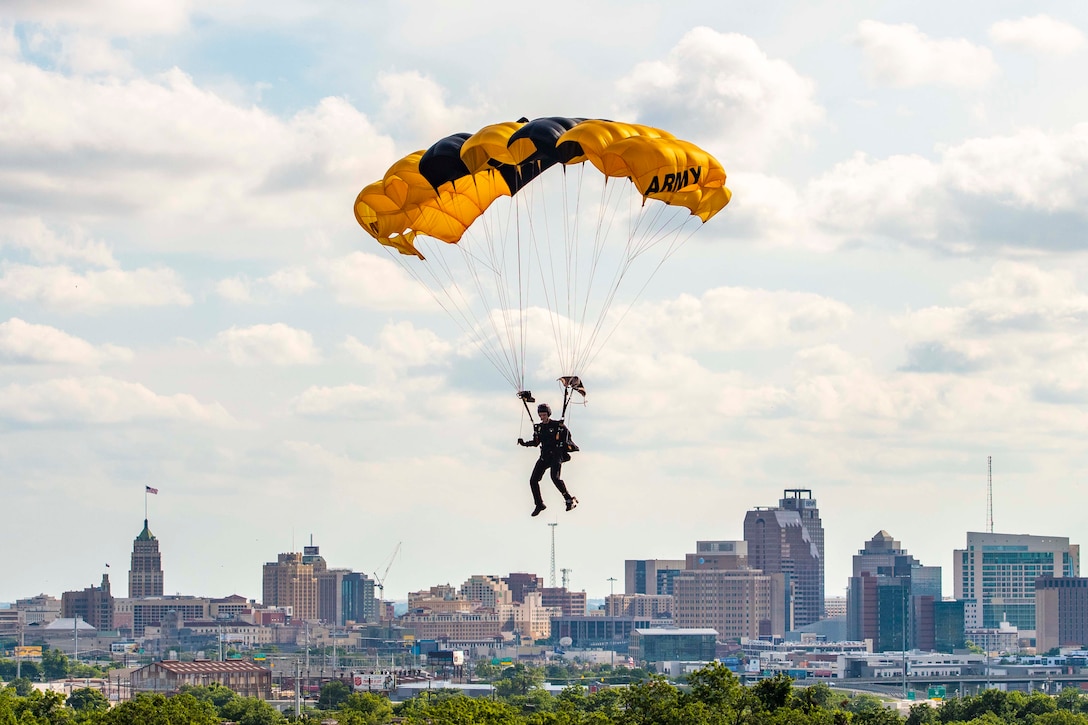 A soldier wearing a parachute descends in the sky.