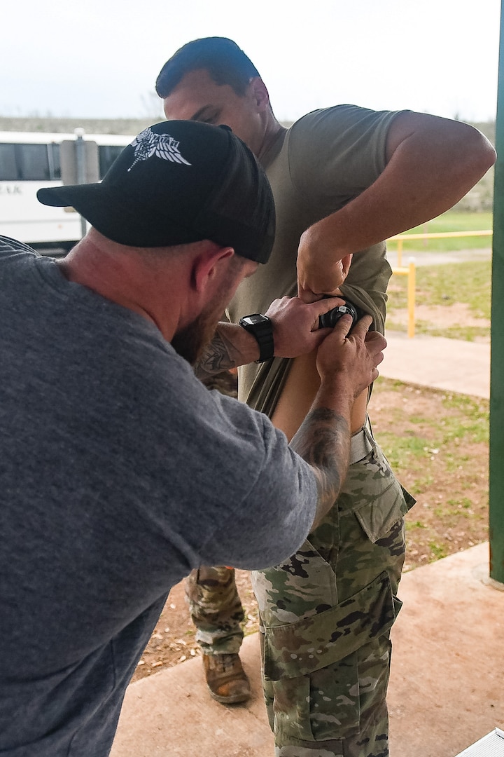 Air Force civilian employee attaching wearable tracking device to a training student.
