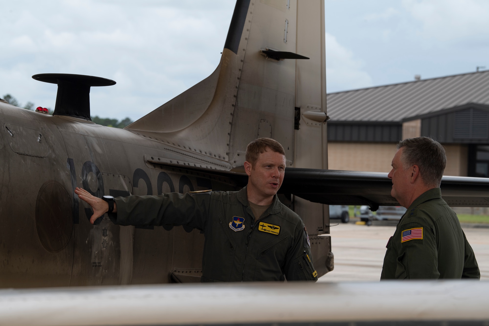 A photo of three Airmen standing on the wing of an Aircraft talking.