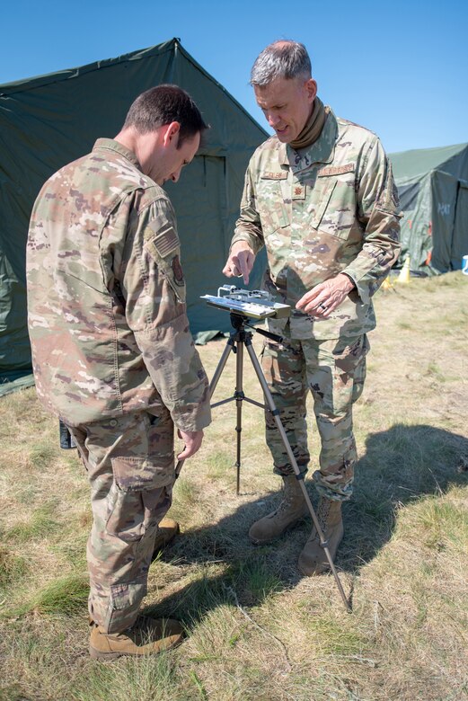 Maj. Kevin Eilers (right), bio-environmental engineer for the Kentucky Air National Guard’s 123rd Contingency Response Group, demonstrates how to use a wet bulb globe temperature apparatus to Master Sgt. Peter Vicini during Operation Lone Oak at Volk Field, Wis., June 9, 2021. The apparatus takes temperature readings to determine work-rest cycles during certain weather conditions, which became crucial for safety during an unprecedented heat wave over the course of the exercise. (U.S. Air National Guard photo by Senior Master Sgt. Vicky Spesard)