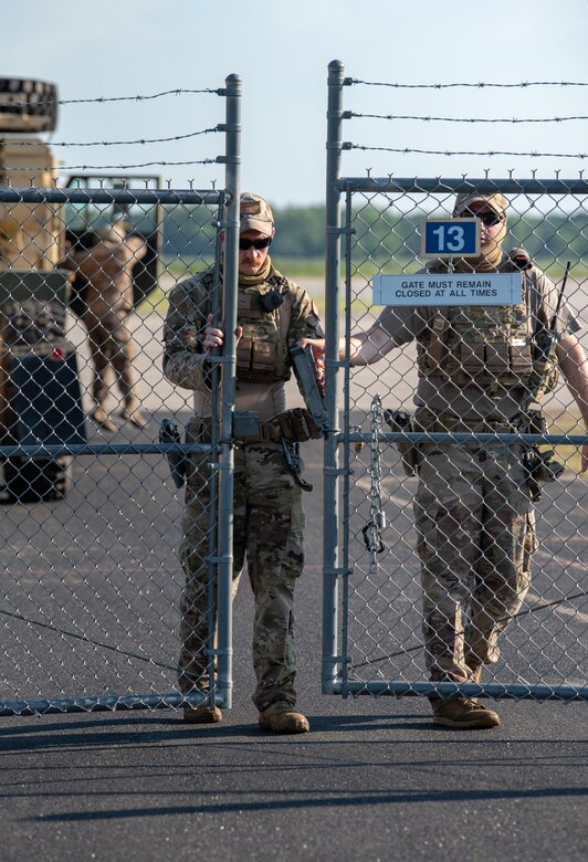 Senior Airman Tyler McCauley and Staff Sgt. Chandler Hunter, security forces specialists with the Kentucky Air National Guard’s 123rd Contingency Response Group, secure the gate during a Joint Task Force-Port Opening exercise known as Operation Lone Oak at Volk Field, Wis., June 11, 2021. The objective of the JTF-PO is to establish a complete air logistics hub and surface distribution network. (U.S. Air National Guard photo by Senior Master Sgt. Vicky Spesard)