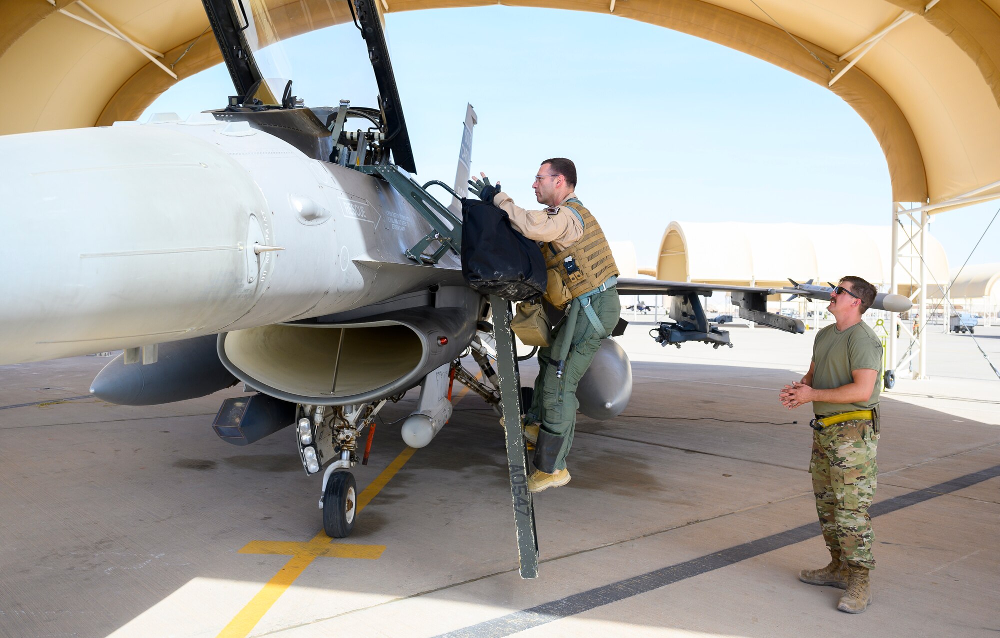 U.S. Air Force Brig. Gen. Robert Davis, 378th Air Expeditionary Wing commander, climbs into a U.S. Air Force F-16 Fighting Falcon, while U.S. Air Force Senior Airman Ryan West, 157th Expeditionary Fighter Generation Squadron F-16 crew chief, prepares to assist in initial flight preparations, Prince Sultan Air Base, Kingdom of Saudi Arabia, June 20, 2021. Davis, a trained fighter pilot, flew his first F-16 sortie with the 157th Expeditionary Fighter Squadron, currently deployed to PSAB to bolster defensive capabilities against potential threats in the region. (U.S. Air Force photo by Senior Airman Samuel Earick)