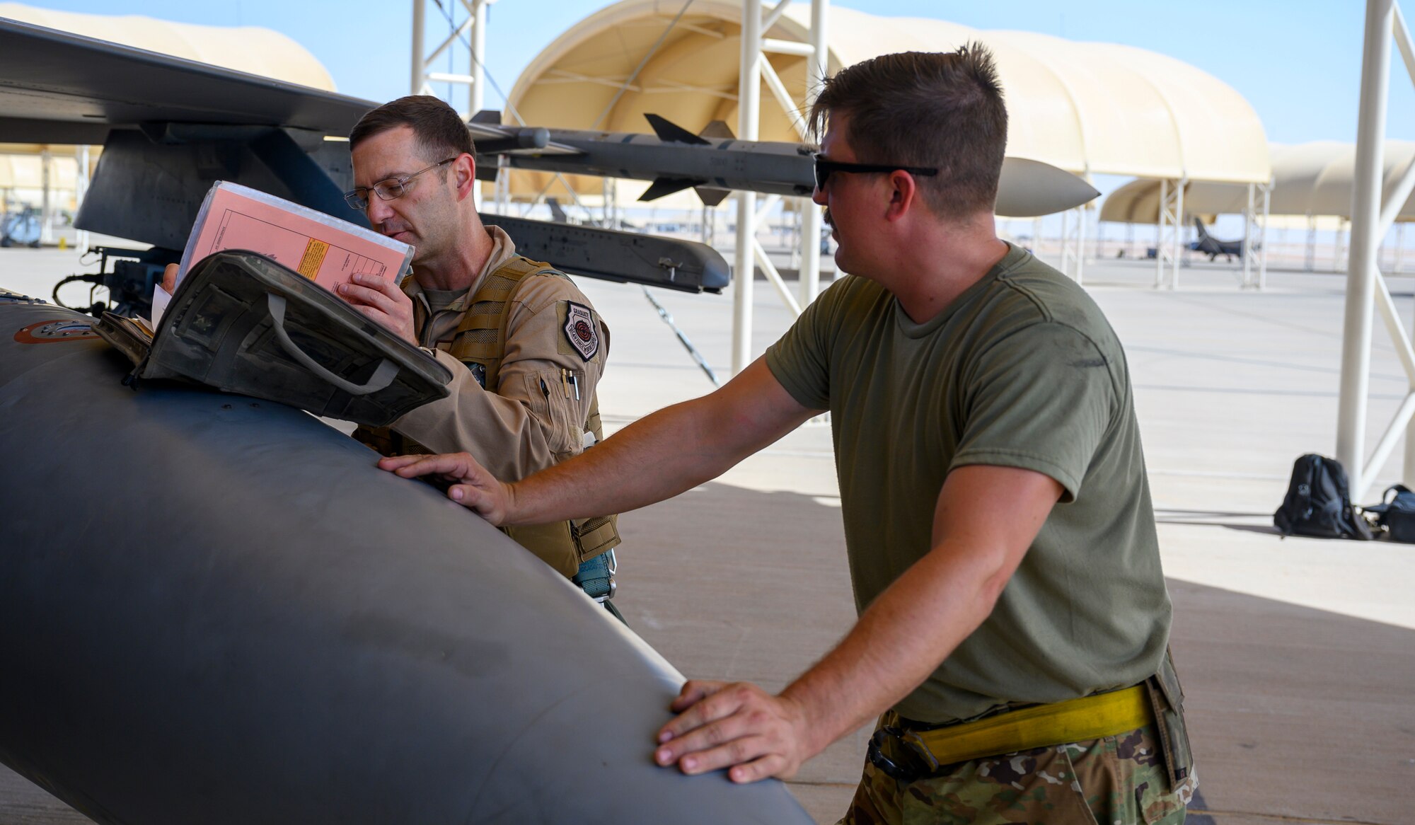 U.S. Air Force Brig. Gen. Robert Davis, 378th Air Expeditionary Wing commander, looks over aircraft documentation on a U.S. Air Force F-16 Fighting Falcon prior to his first flight on base while U.S. Air Force Senior Airman Ryan West, 157th Expeditionary Fighter Generation Squadron F-16 crew chief, stands ready to provide assistance, Prince Sultan Air Base, Kingdom of Saudi Arabia, June 20, 2021. Davis, a trained fighter pilot, flew a sortie with the 157th Expeditionary Fighter Squadron, currently deployed to PSAB to bolster defensive capabilities against potential threats in the region. (U.S. Air Force photo by Senior Airman Samuel Earick)