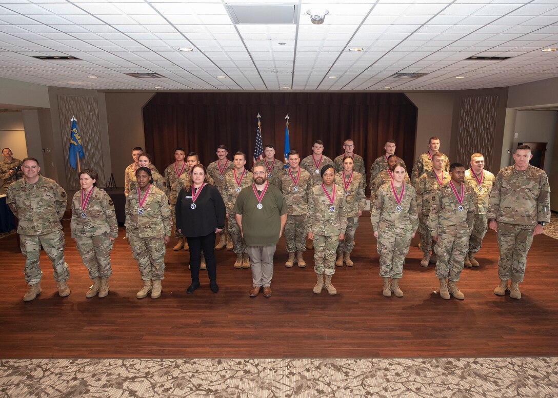 Airman Leadership School Class 21-E poses for a class photo with Col. Michael Phillips (far left), 88th Air Base Wing vice commander, and Chief Master Sgt. Jason Shaffer (far right), 88th ABW command chief, at the end of its graduation ceremony June 17, 2021, inside the  Wright-Patterson Air Force Base, Ohio, Club and Banquet Center. (U.S. Air Force photo by R.J. Oriez)