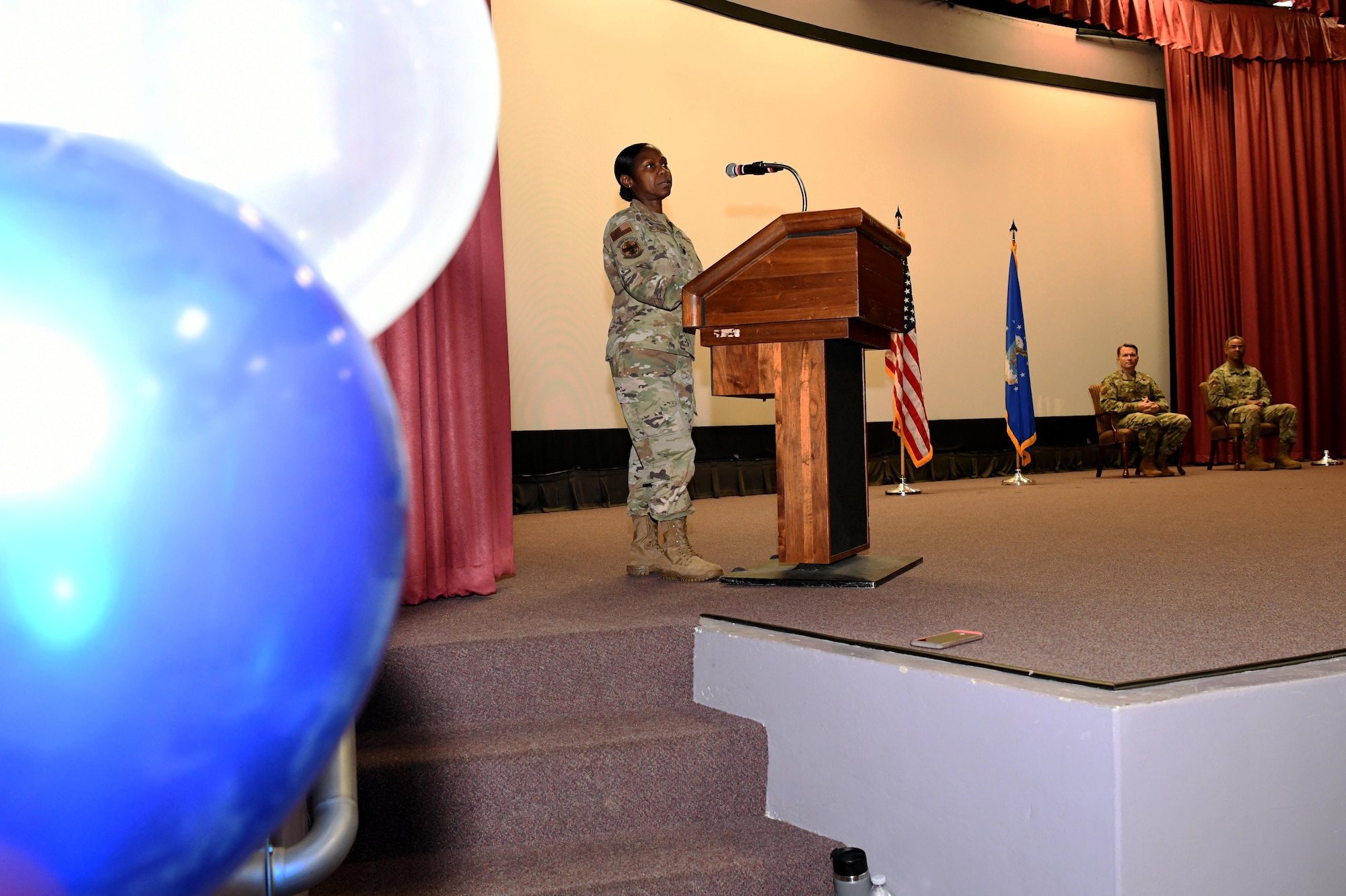 Photo shows Airman standing behind podium on a stage.
