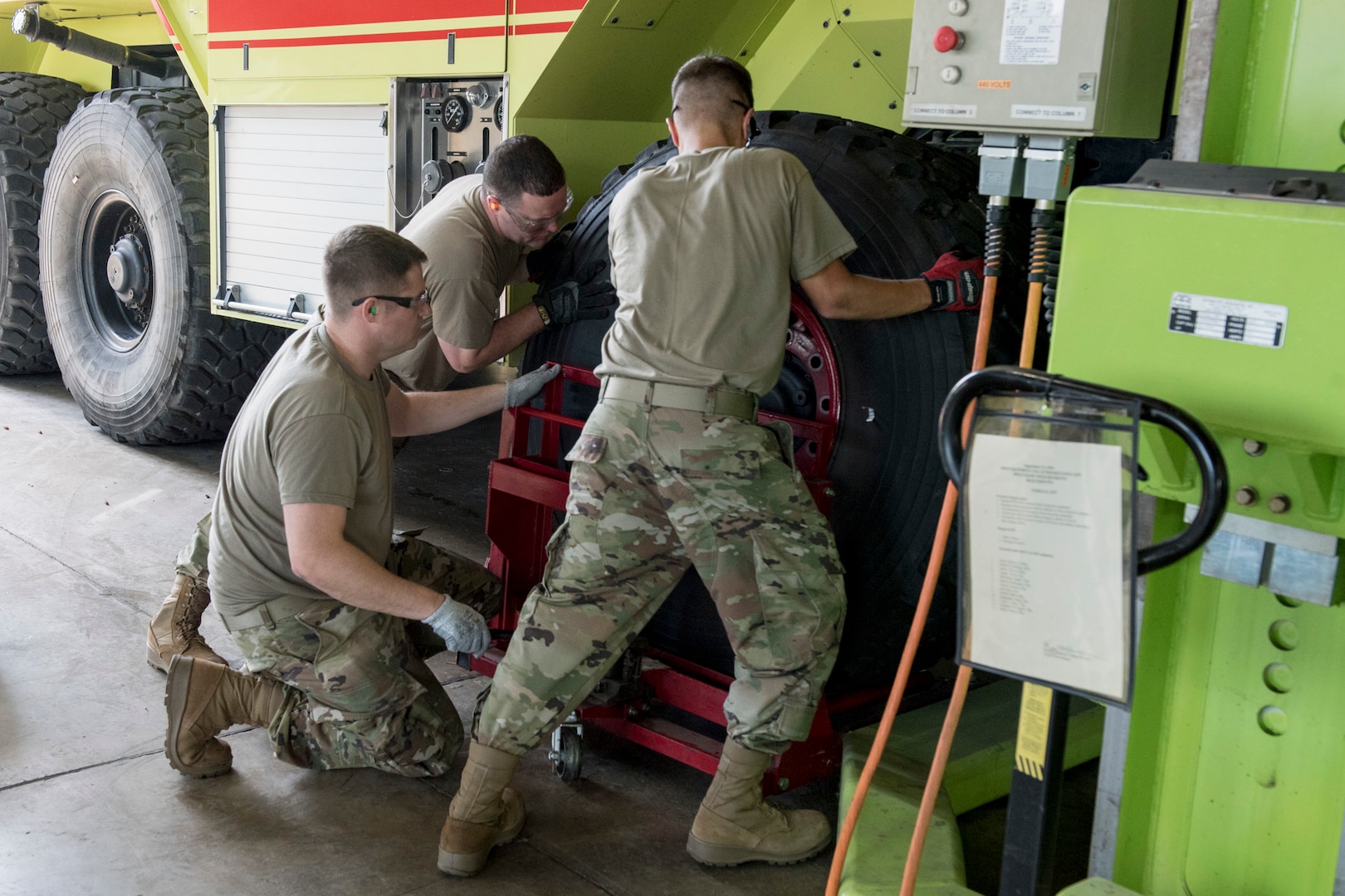 Left to right, Air Force Staff Sgts. Seth Hott, Steven Spitzer and Dallas Nichols, vehicle maintainers with the 167th Logistics Readiness Squadron, West Virginia Air National Guard, place a wheel and tire on a firetruck at the 167th Airlift Wing, Martinsburg, West Virginia, June 10, 2021.