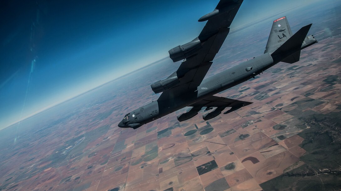 A jet flies over farmland.