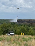 Soldiers flying a Nebraska Army National Guard CH-47 Chinook helicopter above the Spring Creek division of the Brush Creek fire drop water from a 2,000-gallon bucket June 25, 2021, in Holt County, Nebraska.