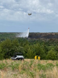 Soldiers flying a Nebraska Army National Guard CH-47 Chinook helicopter above the Spring Creek division of the Brush Creek fire drop water from a 2,000-gallon bucket June 25, 2021, in Holt County, Nebraska.