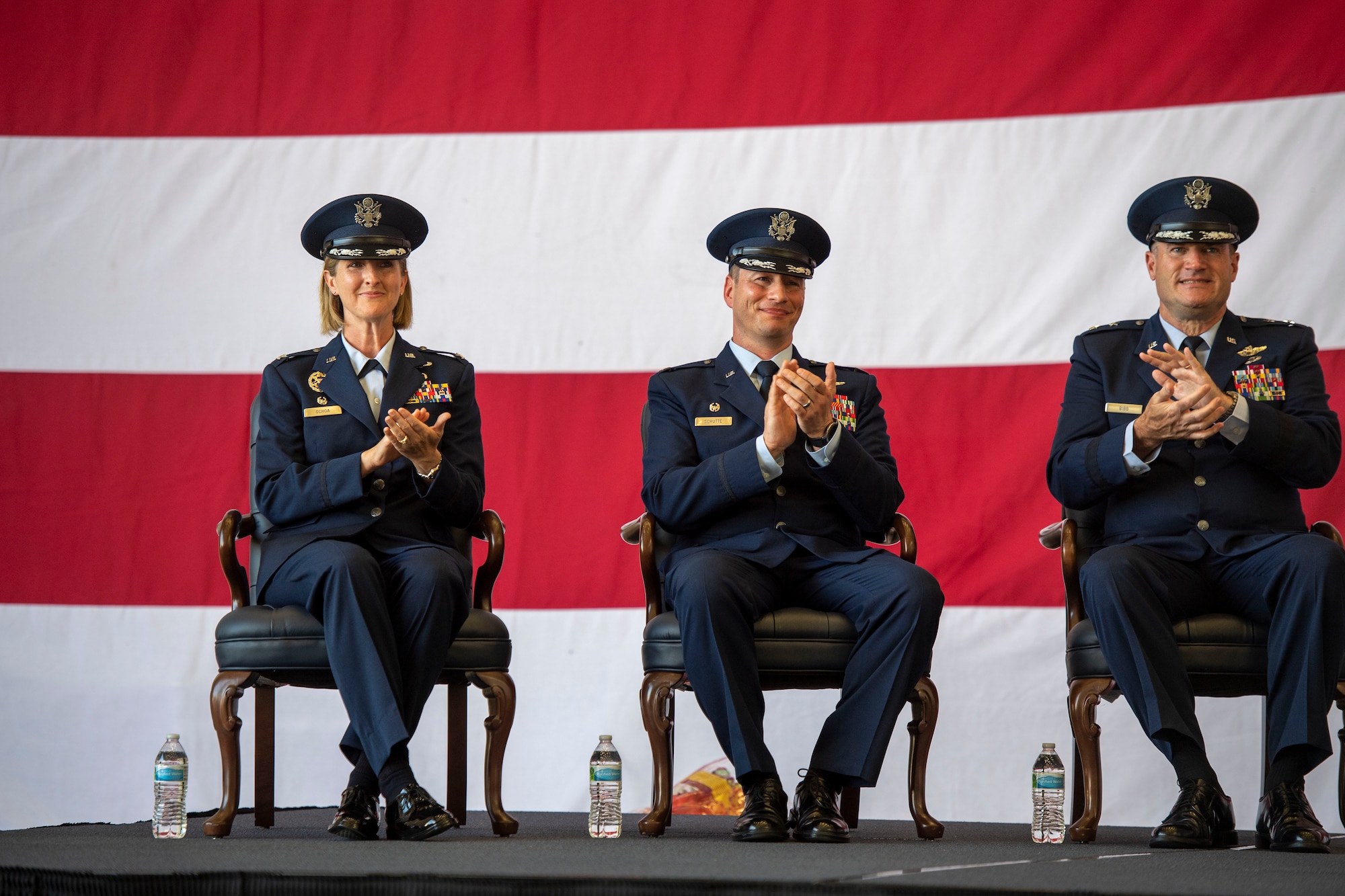 Airmen sit on stage during a change of command ceremony.