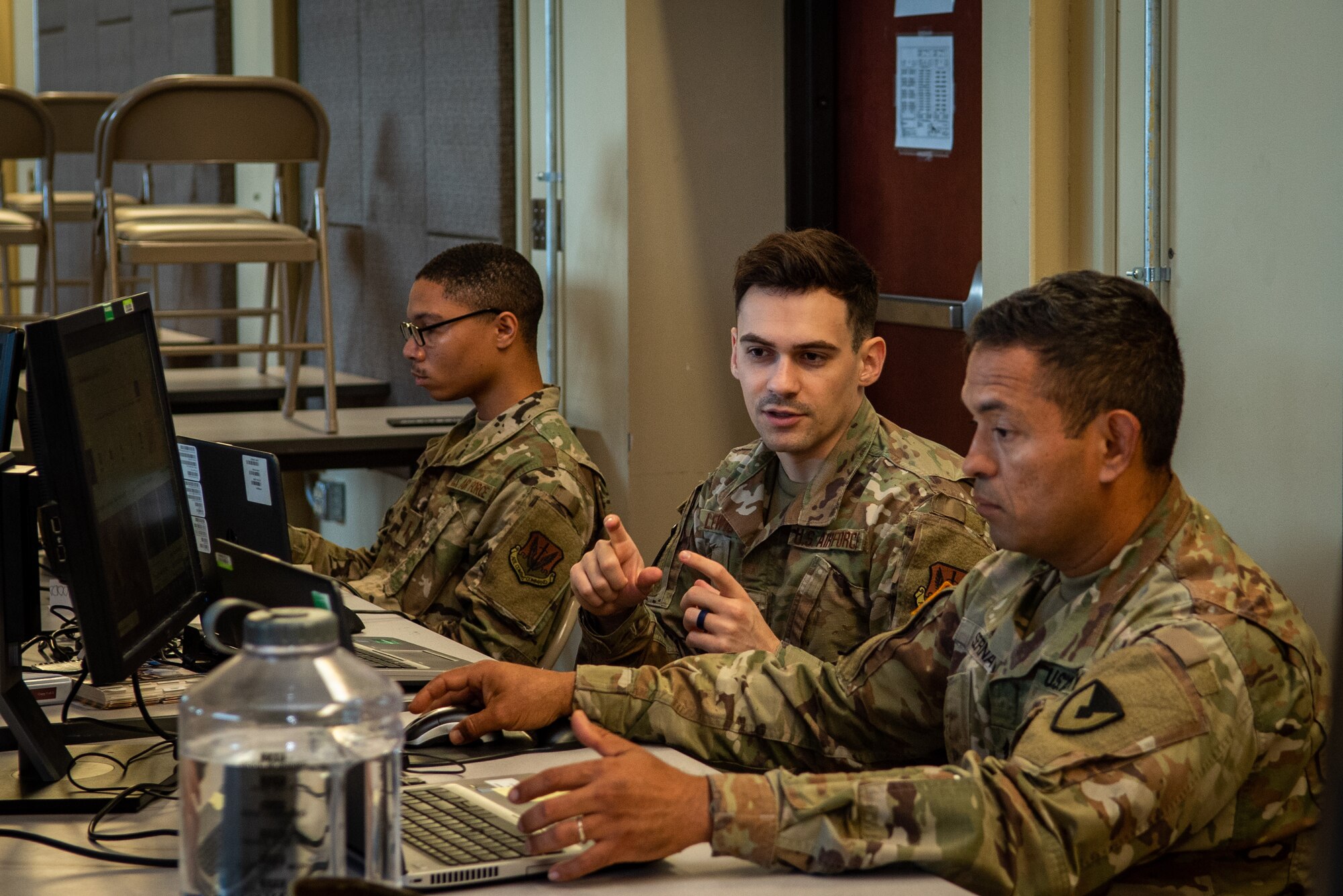 Army Staff Sgt. Antonio Cusic, front, 419th Contracting Support Brigade contracting specialist, Air Force Staff Sgt. Joshua Lewis, 4th Contracting Squadron contracting specialist, and 2nd Lt. Ian Woods 4th CONS infrastructure flight team lead, work on computers at Fort Bragg, North Carolina, June 24, 2021. Joint Forces Contracting Exercise 2021 required contracting teams to execute the force employment concept of deploying a joint regional contracting office to provide operational contract support to a combat-credible force in the deterrence of aggression against U.S. interests in key areas. (U.S. Air Force Photo by Airman 1st Class David Lynn)