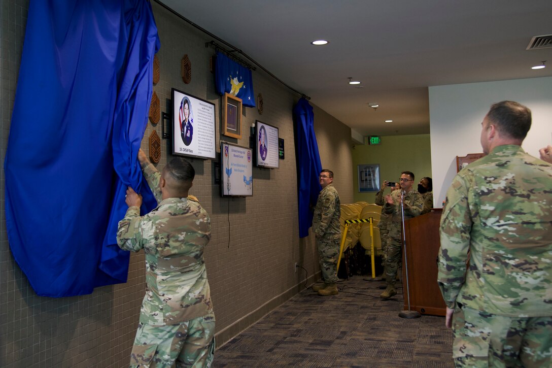 Participants of an unveiling ceremony pull back the curtains to reveal an Enlisted Heritage wall at the South Bay Bar and Grill on Los Angeles Air Force Base, Calif., June 24, 2021. The wall is titled "CMSgt Lisa Arnold Enlisted Heritage Wall" after the current Space and Missile Systems Center's Command Chief Master Sgt. Lisa A. Arnold who will be the last U.S. Air Force command chief for Los Angeles AFB before being replaced by a U.S. Space Force Senior Enlisted Leader. (U.S. Space Force photo by Staff Sgt. Elijah Jackson)