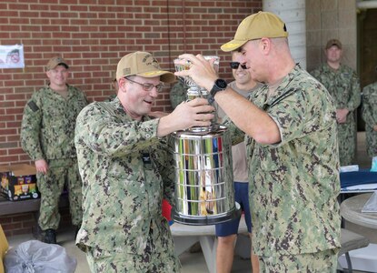 NAVAL STATION NORFOLK (June 25, 2021) Rear Adm. Brendan McLane, the commander of Naval Surface Force Atlantic (SURFLANT), presents the small-command SURFLANT Surface Line Week (SLW) trophy to the San Antonio-class amphibious transport dock ship PCU Fort Lauderdale (LPD 28). An annual competition hosted by Naval Surface Force Atlantic (SURFLANT) for all subordinate SURFLANT commands, SLW sees Hampton Roads-based service members from the Navy and Marine Corps unite to participate in camaraderie-building events and contests. (U.S. Navy photo by Mass Communication Specialist 2nd Class Jacob Milham/Released)