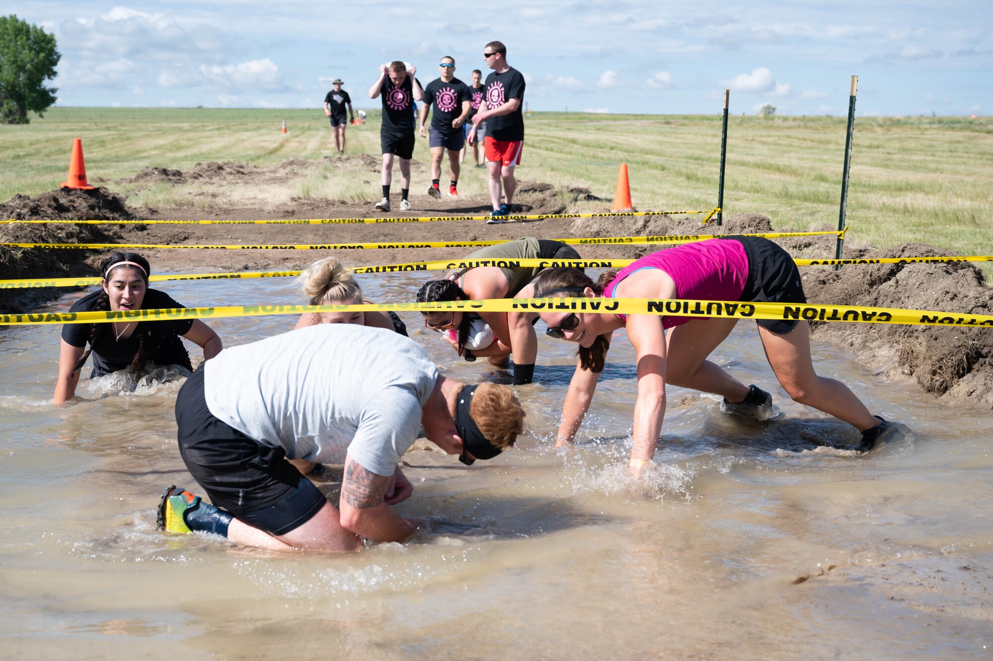 Members of the 341st Missile Wing crawl below caution tape during the Filthy Mudder race June 25, 2021, at Malmstrom Air Force Base, Mont.
