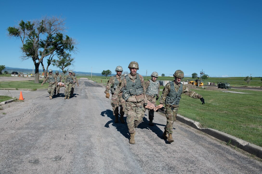 Airmen carry a manikin on a stretcher