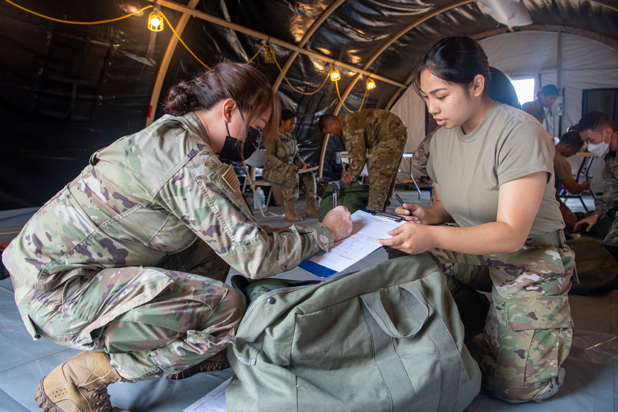 Staff Sgt. Veleeca Conley signs for chemical gear that was issued to her by Airman 1st Class Darlene Ibarra during Pacific Warriorz 2021 (PWZ-21). PWZ-21 is a Total Force Integration and Joint Training exercise at Schofield Barracks, Hawaii June 12, 2021.