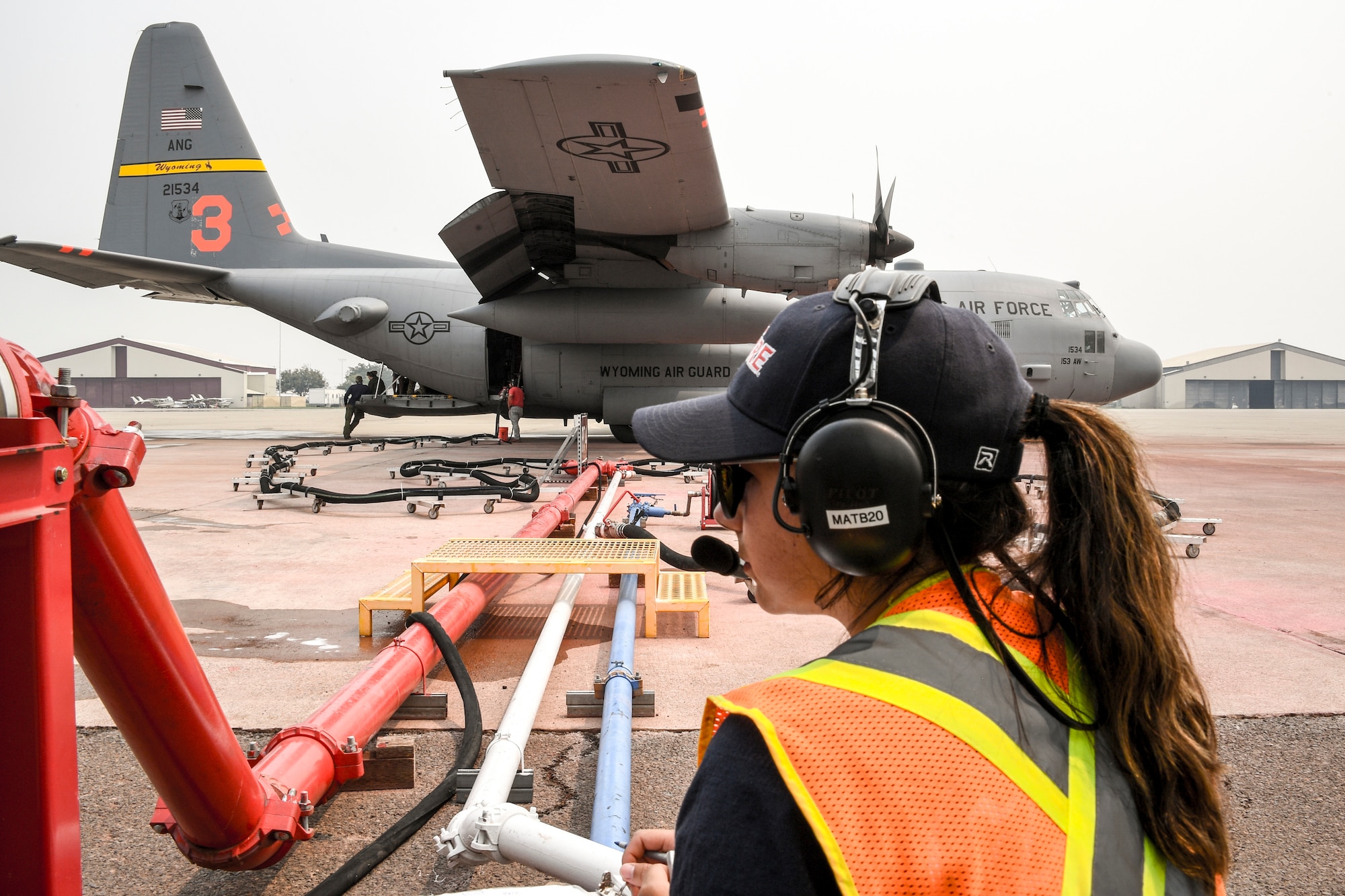 A CALFIRE member meters fire retardant being loaded onto a U.S. Air National Guard C-130H Hercules from the 153rd Airlift wing out of Wyoming, used in airborne firefighting operations, at McClellan Air Park, California, Aug. 21, 2020. C-130s equipped with Modular Airborne Firefighting System II from Wyoming and California worked with other firefighting aircraft to battle fires throughout Northern California.