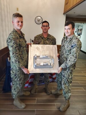 NAVAL STATION NORFOLK (June 16, 2021) Sailors from Assault Craft Unit 4 display their winning entry in the Naval Surface Force Atlantic Surface Line Week welding competition. Each welder had one week to create a product that represented their command such as the command’s motto, insignia, history, or namesake. (Photo courtesy of Kat Ciesielski/Released)