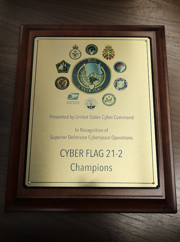 A photo shows a plaque bearing the words Cyber Flag 21-2 champions.