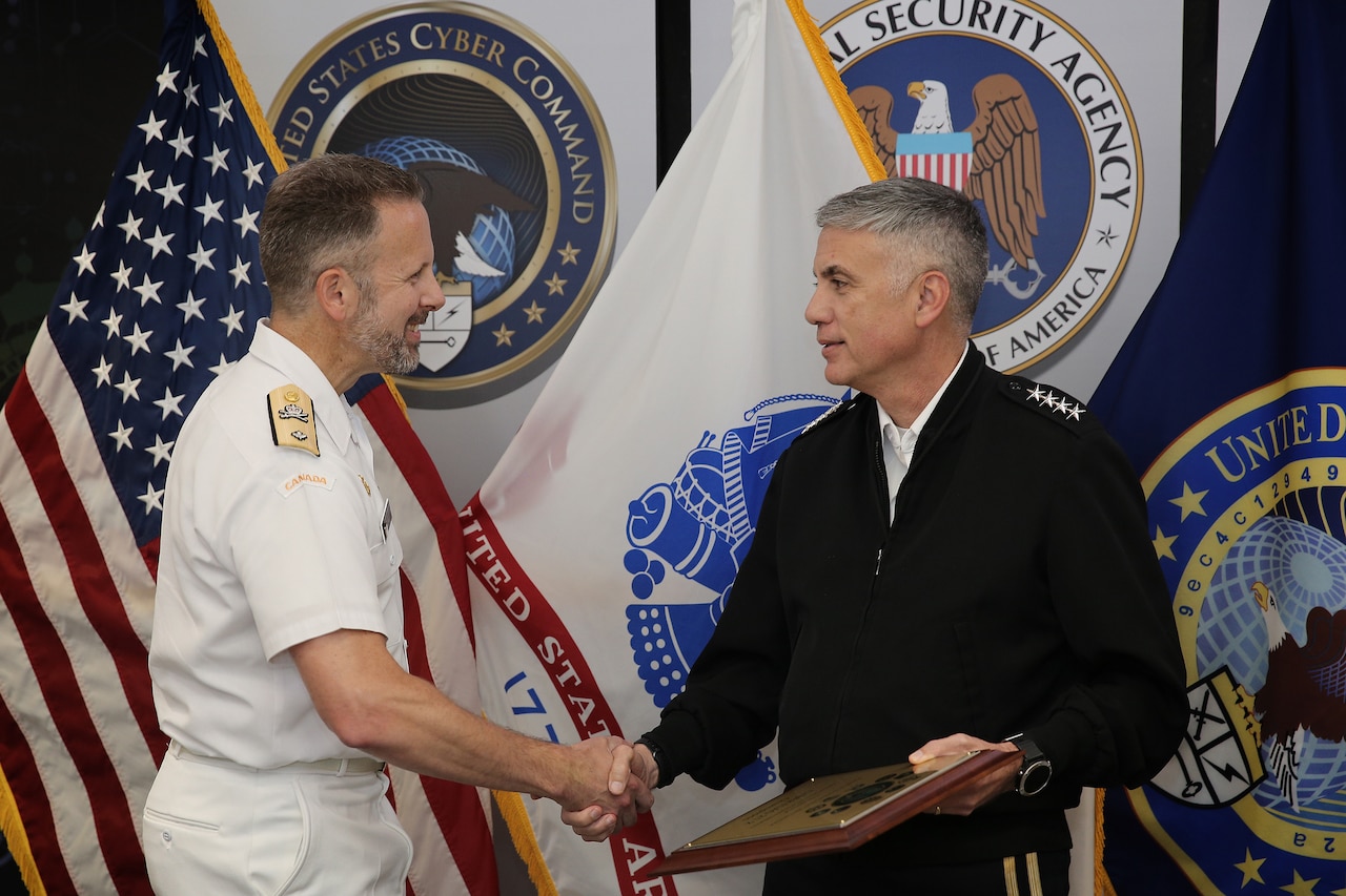 Two men wearing uniforms shake hands.