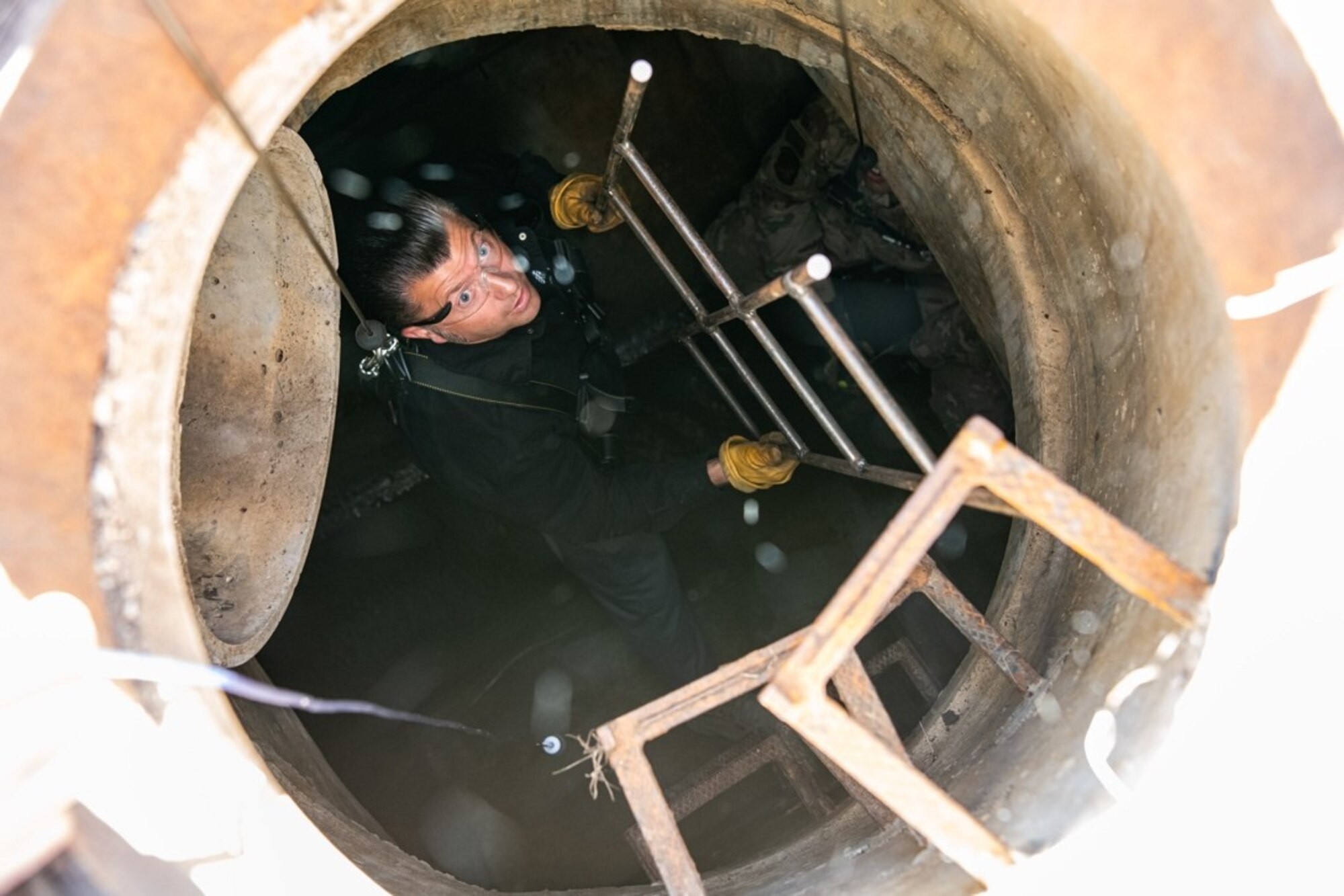 Ken Long, an engineering equipment operator assigned to the 28th Civil Engineer Squadron, hands a grate up to Airmen waiting outside of a confined space on Ellsworth Air Force Base, S.D., May 18, 2021.