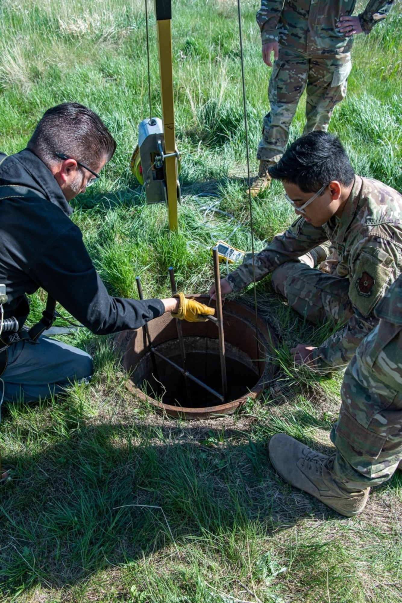 Ken Long, an engineering equipment operator assigned to the 28th Civil Engineer Squadron, and Airman 1st Class Joshua Tabasa, a heavy equipment operator assigned to the 28th Civil Squadron, lower equipment down into a confined space on Ellsworth Air Force, S.D., May 18, 2021.