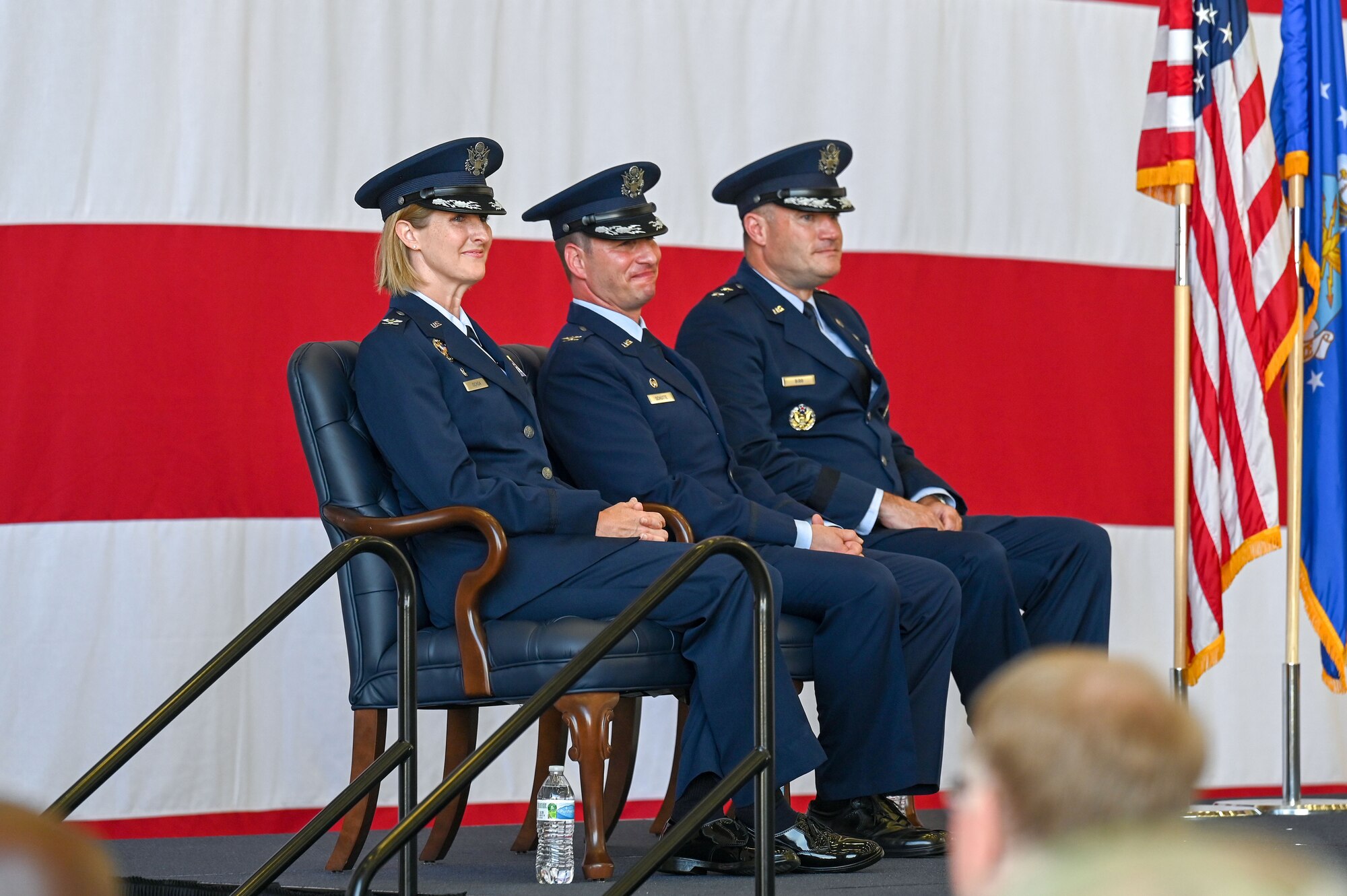 Airmen sit on stage during a change of command ceremony.