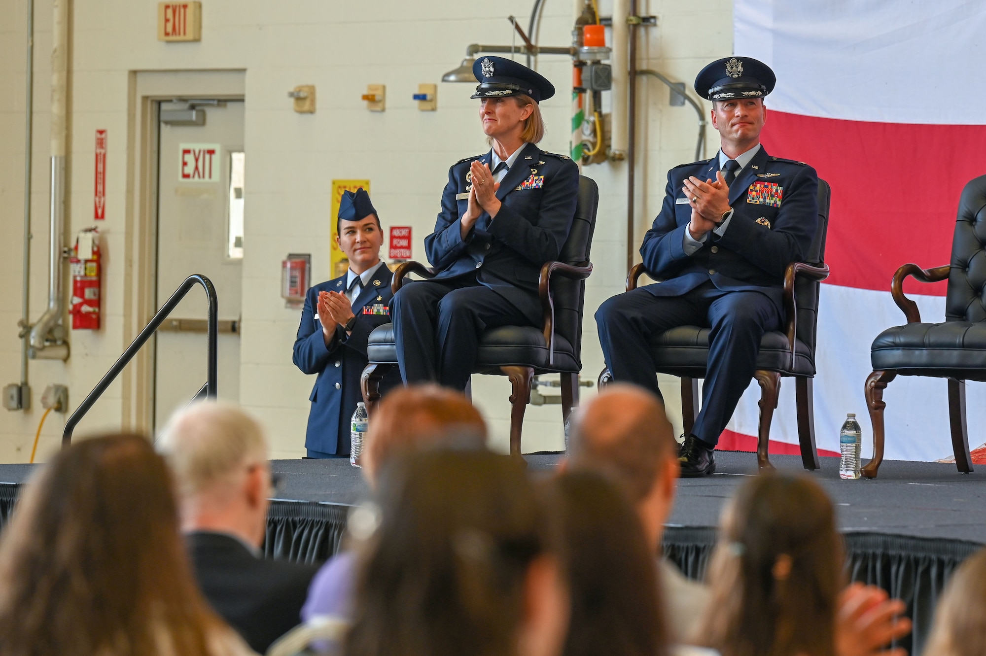 Airmen sit on stage during a change of command ceremony.