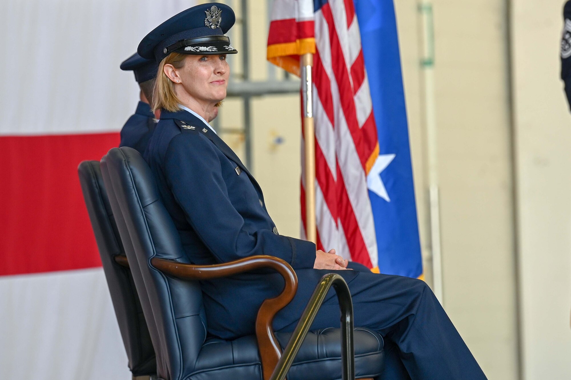 An Airman sits on stage during a change of command ceremony.